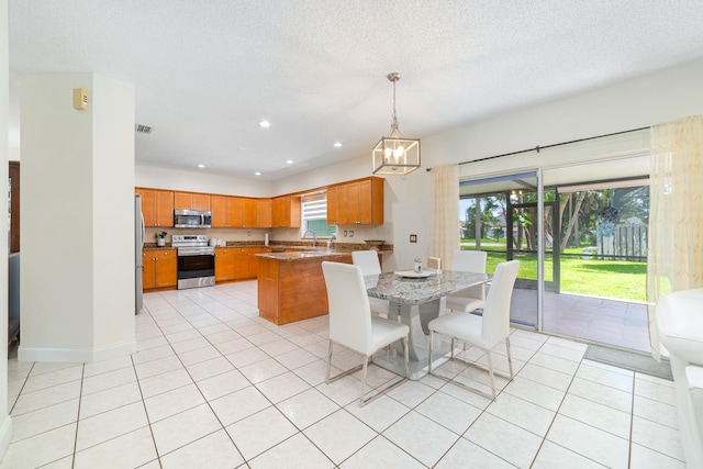 kitchen featuring a kitchen island, appliances with stainless steel finishes, light tile patterned floors, sink, and decorative light fixtures