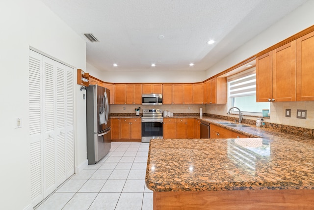 kitchen with dark stone counters, tasteful backsplash, light tile patterned floors, sink, and stainless steel appliances