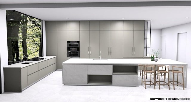 kitchen with a large island with sink, double oven, a kitchen breakfast bar, gray cabinetry, and sink