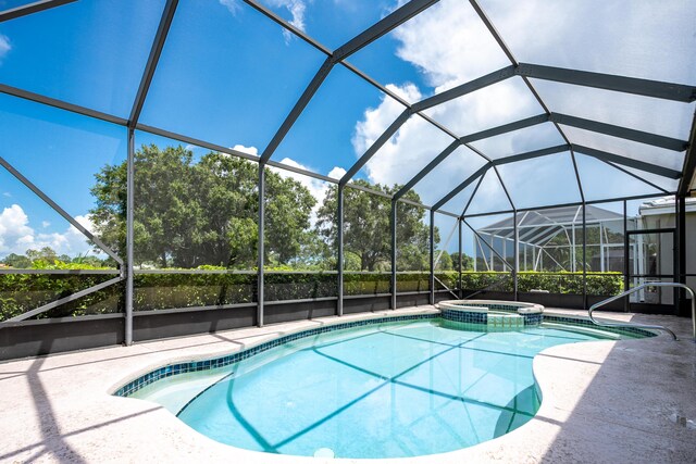 view of pool with glass enclosure, an in ground hot tub, and a patio