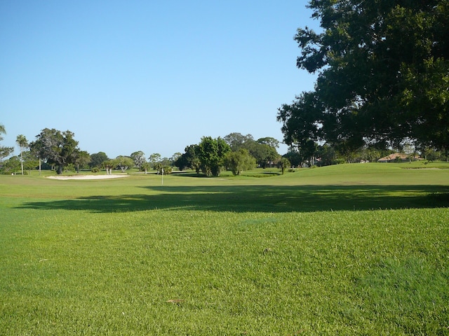 view of property's community with golf course view and a lawn