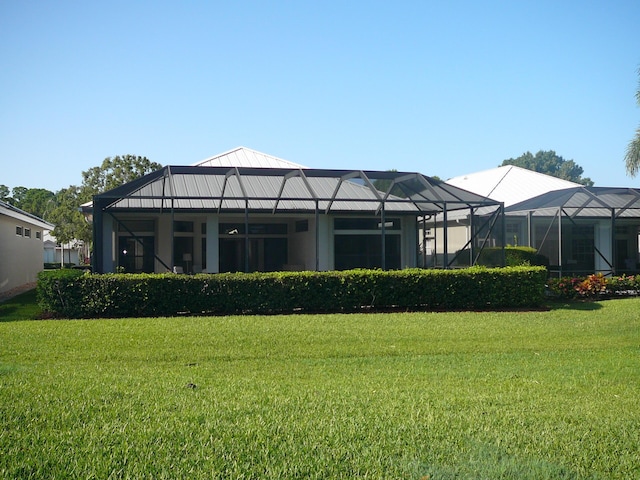 back of house with a lanai and a lawn