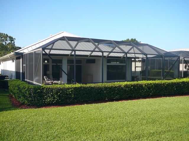 rear view of property with a yard and a lanai