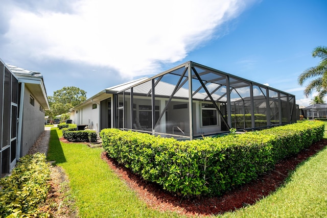 rear view of house with a lanai and a lawn