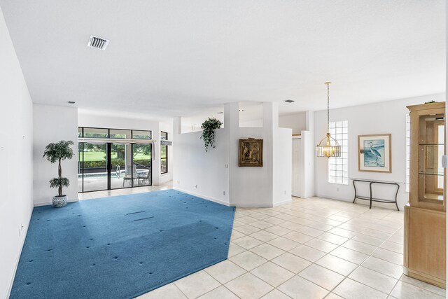 empty room with a notable chandelier and light tile patterned floors