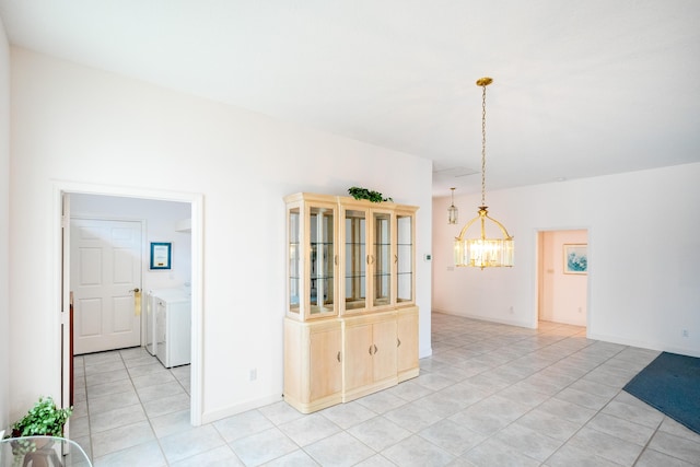 unfurnished dining area with an inviting chandelier, light tile patterned floors, baseboards, and washer and dryer