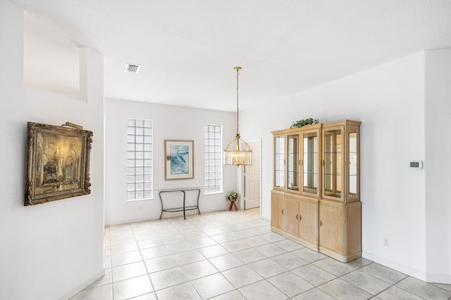 spare room featuring light tile patterned floors, baseboards, visible vents, and an inviting chandelier