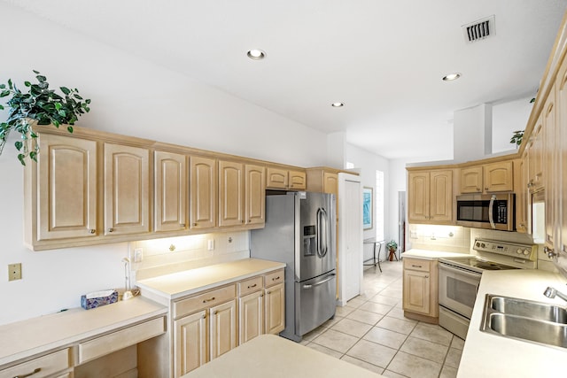 kitchen with stainless steel appliances, light countertops, decorative backsplash, light brown cabinets, and a sink