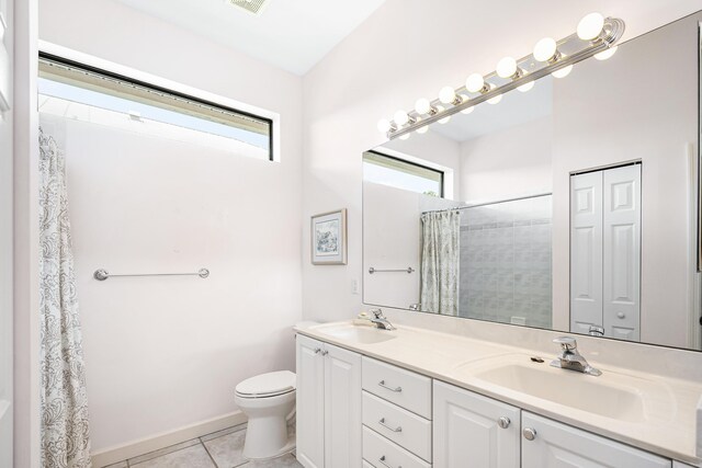 bathroom featuring tile patterned floors, double vanity, and toilet