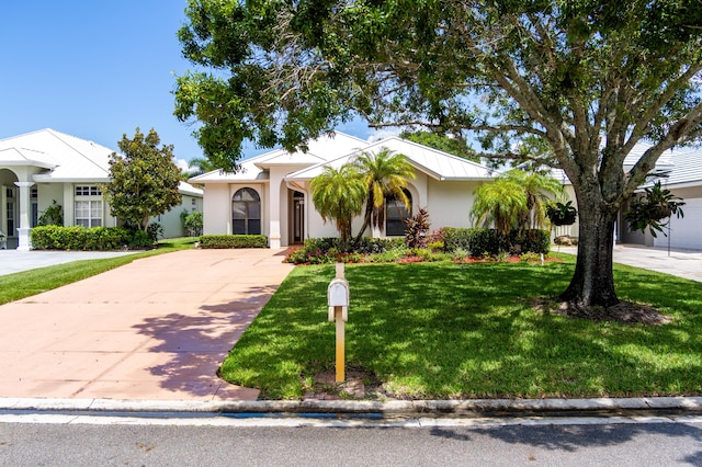 view of front of property with metal roof, concrete driveway, a front yard, and stucco siding