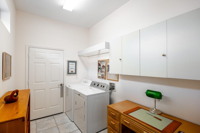 laundry area with washing machine and clothes dryer, cabinets, and light tile patterned flooring