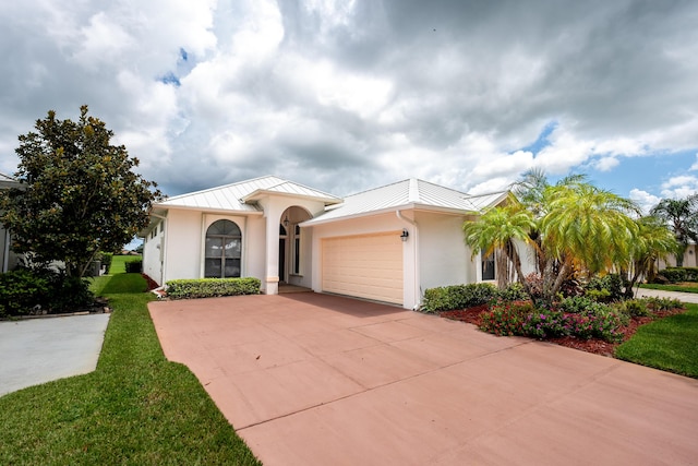 mediterranean / spanish home featuring concrete driveway, metal roof, an attached garage, a standing seam roof, and stucco siding