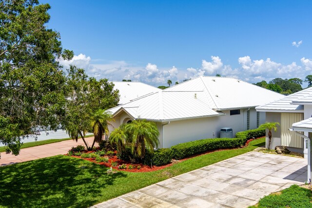 view of side of property with a lawn and central AC unit