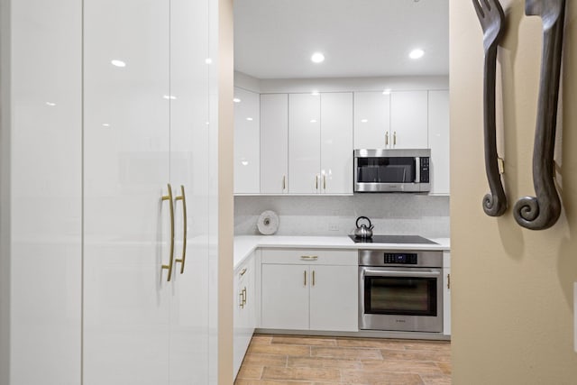 kitchen featuring backsplash, stainless steel appliances, light hardwood / wood-style floors, and white cabinets