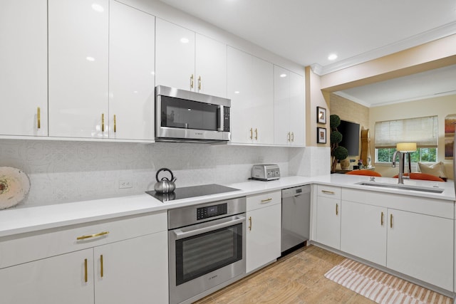 kitchen with stainless steel appliances, light hardwood / wood-style floors, tasteful backsplash, sink, and white cabinets