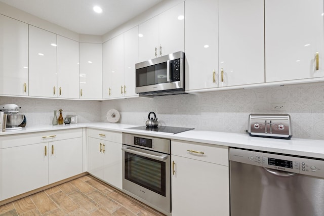 kitchen featuring white cabinets, tasteful backsplash, light hardwood / wood-style flooring, and appliances with stainless steel finishes