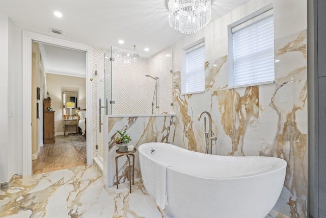 bathroom with tile walls, an inviting chandelier, a bath, and wood-type flooring