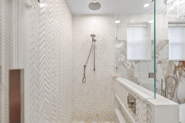 bathroom with tile walls, a notable chandelier, and a tile shower