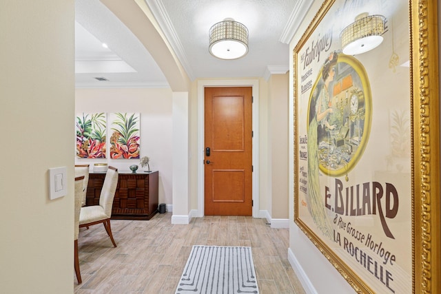 foyer featuring light hardwood / wood-style floors, crown molding, and a textured ceiling