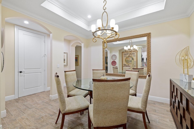 dining room featuring light hardwood / wood-style floors, a raised ceiling, ornamental molding, and a chandelier