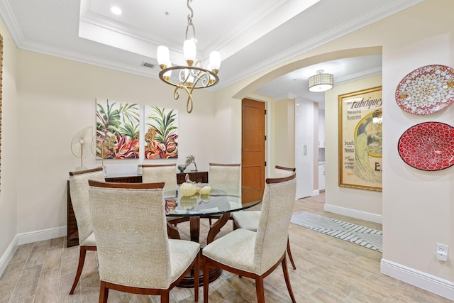 dining room featuring light hardwood / wood-style floors, a raised ceiling, and crown molding