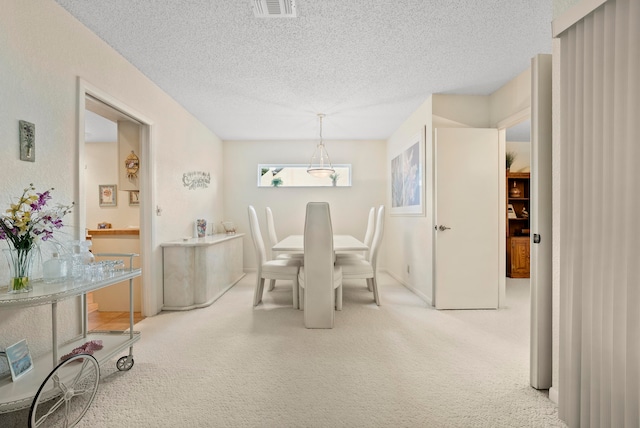 dining space featuring light colored carpet and a textured ceiling