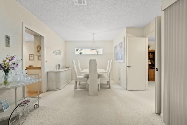 dining area with visible vents, a textured ceiling, and carpet flooring