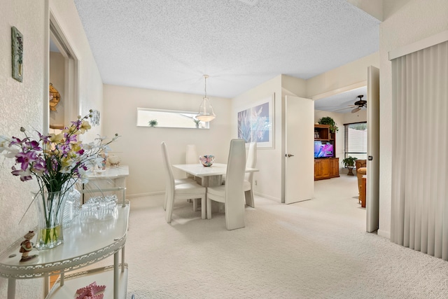 dining area featuring ceiling fan, a textured ceiling, and light carpet