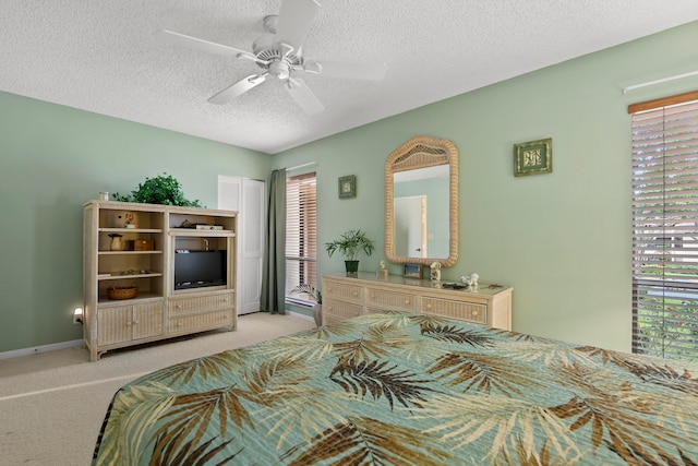 carpeted bedroom featuring ceiling fan and a textured ceiling