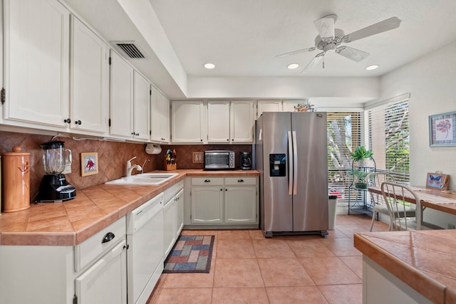 kitchen featuring appliances with stainless steel finishes, tasteful backsplash, sink, light tile patterned floors, and ceiling fan