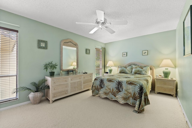 carpeted bedroom with ceiling fan, baseboards, and a textured ceiling