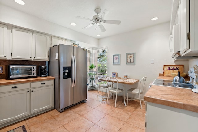 kitchen featuring ceiling fan, white cabinetry, stainless steel fridge, and light tile patterned floors