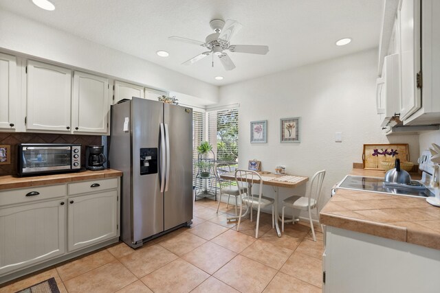 kitchen with light tile patterned floors, a toaster, white cabinets, stainless steel refrigerator with ice dispenser, and tasteful backsplash