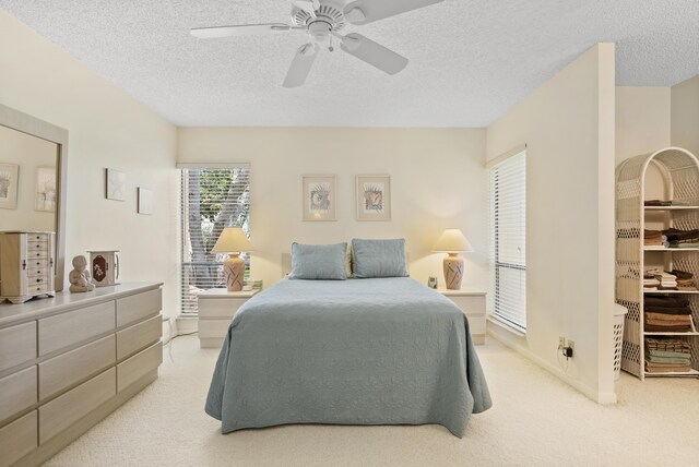 bedroom featuring light carpet, ceiling fan, and a textured ceiling