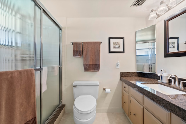 bathroom with tile patterned flooring, toilet, vanity, and walk in shower