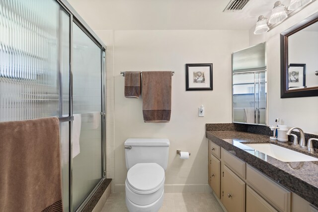 bathroom featuring toilet, vanity, visible vents, baseboards, and a stall shower