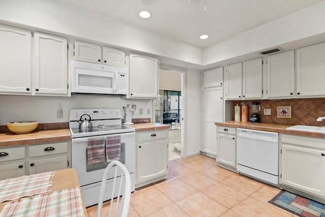 kitchen with decorative backsplash, white cabinetry, sink, light tile patterned flooring, and white appliances