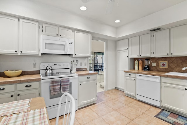 kitchen with white appliances, white cabinetry, a sink, and light tile patterned floors