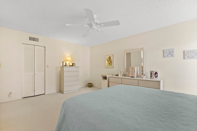 bedroom featuring light colored carpet, a closet, a textured ceiling, and ceiling fan