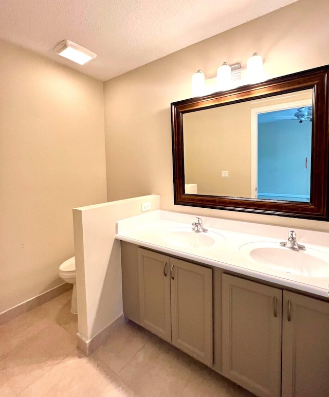 bathroom featuring tile patterned flooring, double sink vanity, a textured ceiling, and toilet