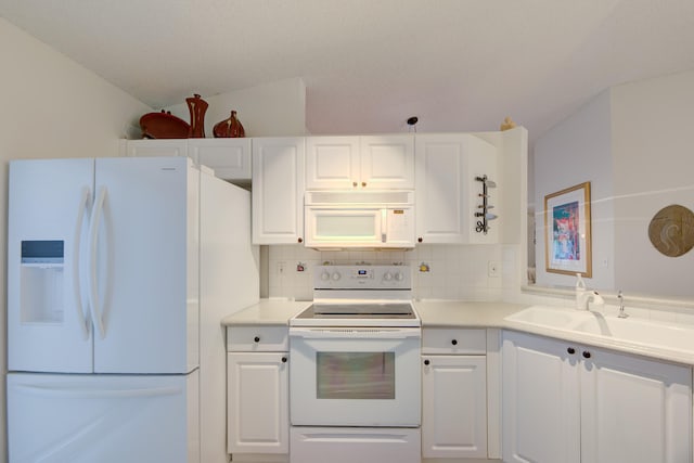 kitchen featuring white appliances, backsplash, white cabinetry, and vaulted ceiling