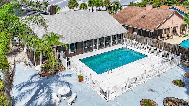 view of swimming pool featuring a sunroom and a patio area