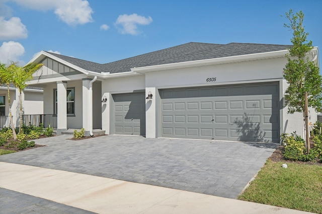 ranch-style house with roof with shingles, decorative driveway, an attached garage, and stucco siding