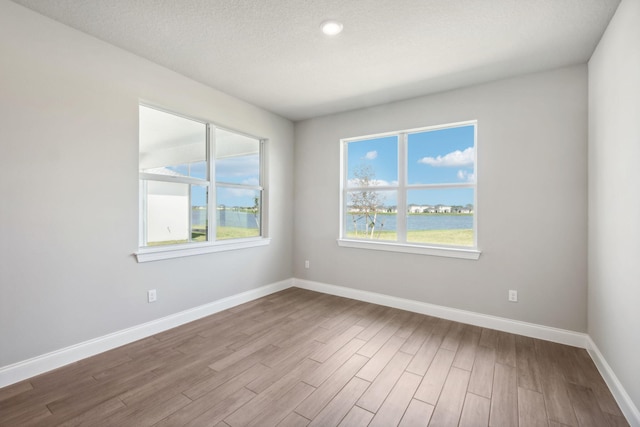 spare room featuring a textured ceiling and light wood-type flooring