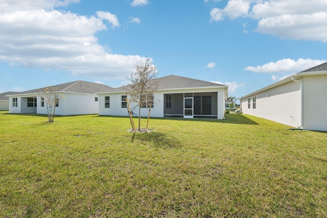 rear view of house featuring a lawn and a sunroom