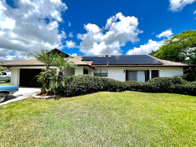 ranch-style home featuring a garage, solar panels, and a front yard