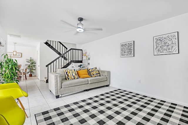 living room featuring light tile patterned floors, ceiling fan, and stairway