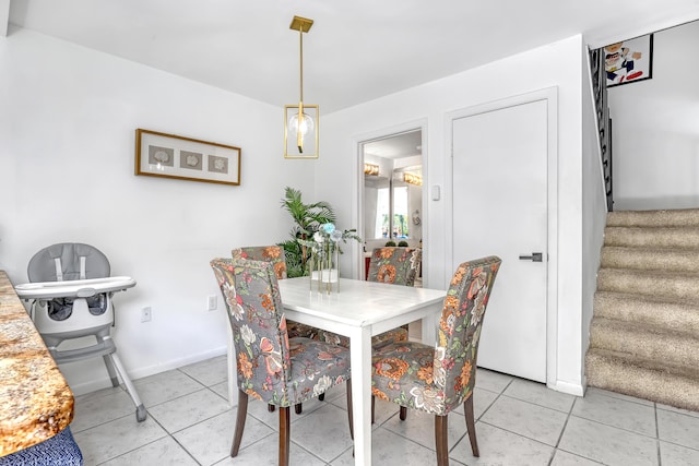 dining area featuring light tile patterned floors, baseboards, and stairs