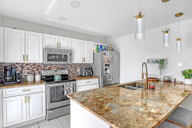 kitchen with stainless steel appliances, a peninsula, a sink, white cabinetry, and decorative light fixtures