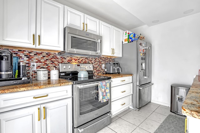 kitchen featuring light tile patterned floors, backsplash, appliances with stainless steel finishes, white cabinetry, and dark stone counters